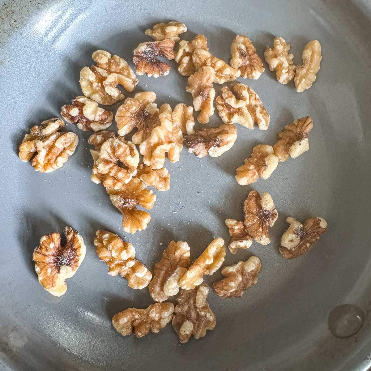 walnuts being toasted in a pan.
