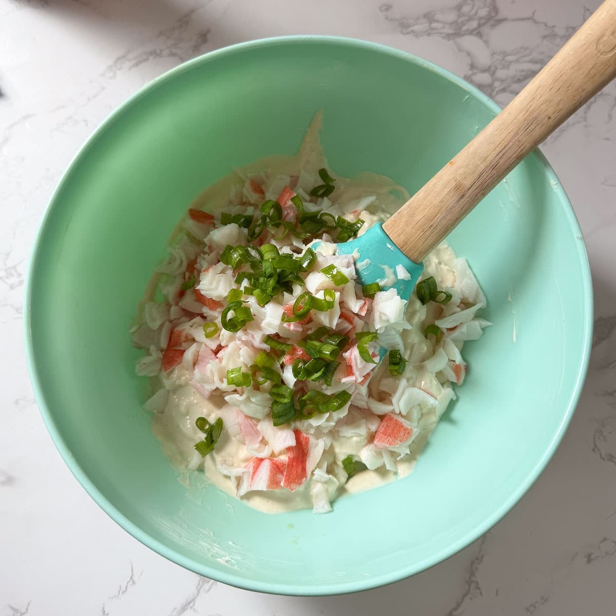 crab and green onions being mixed in.