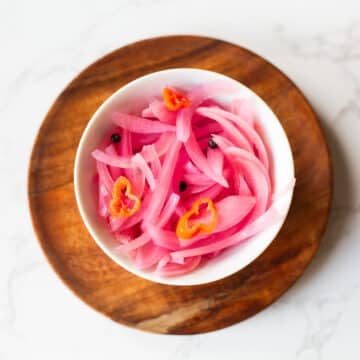 quick pickled red onions in bowl with peppercorns and habanero slices.