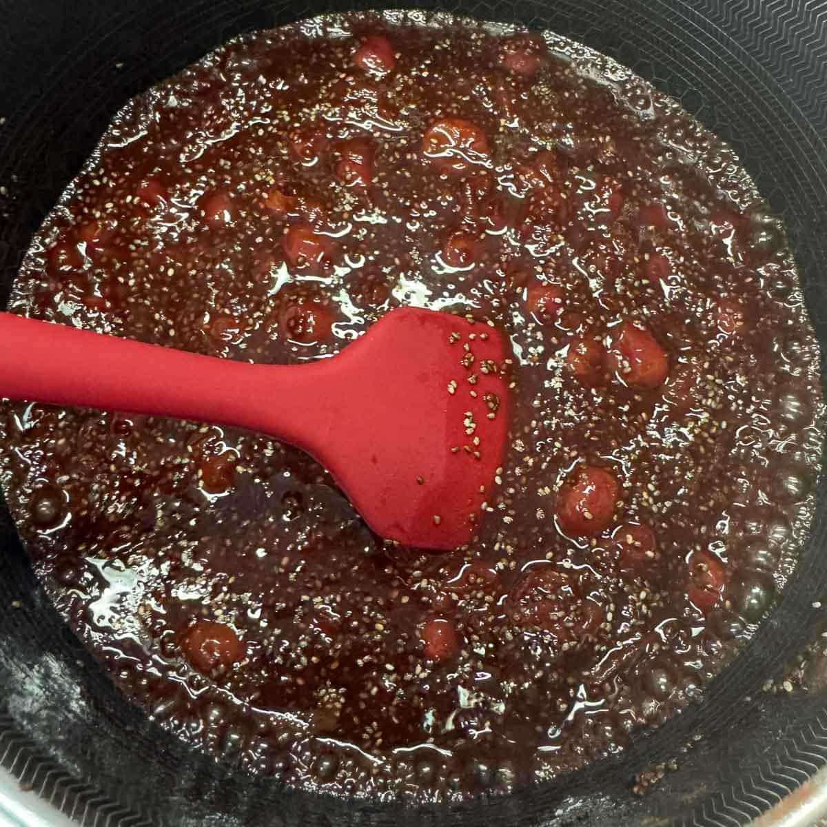 chia seed jam being stirred with a red rubber spatula