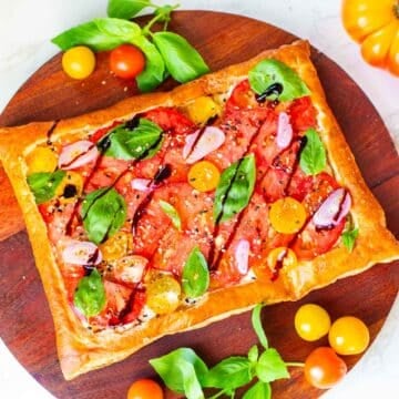 puff pastry tomato tart surrounded by tomatoes and basil.