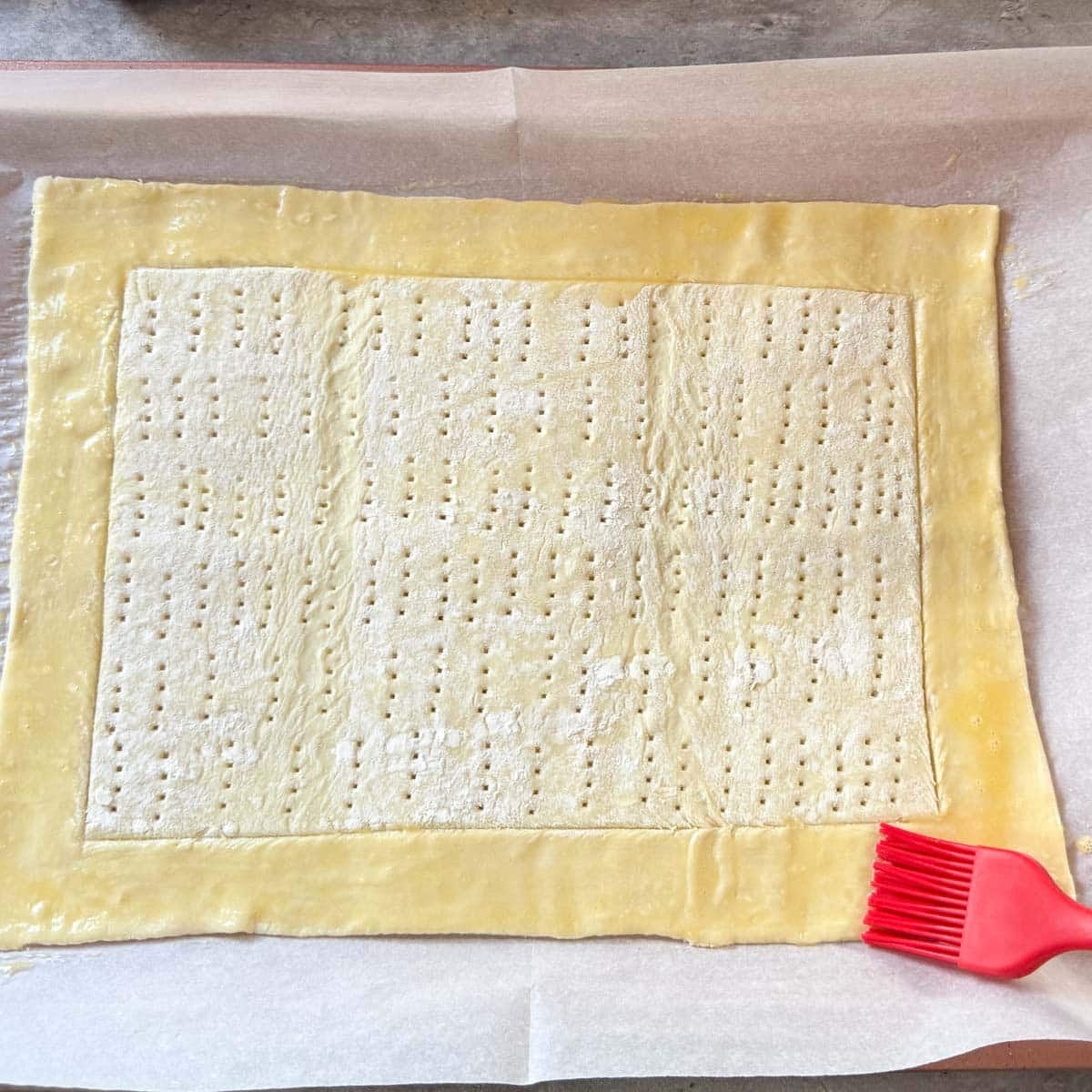 brushing egg wash over pastry border.