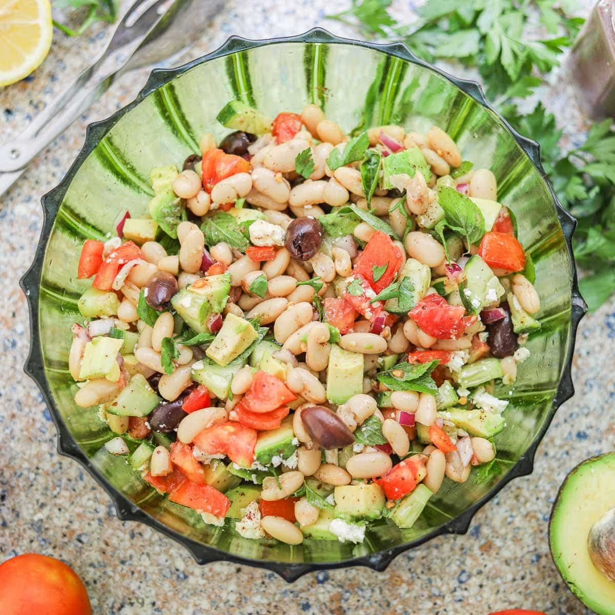 white bean salad in a green bowl with veggies around it