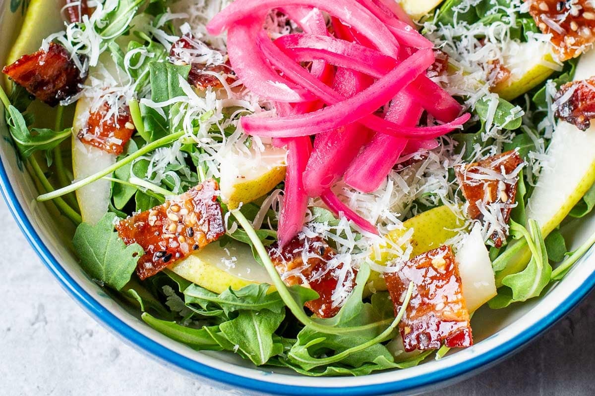 candied bacon in a salad with arugula and pickled onions.