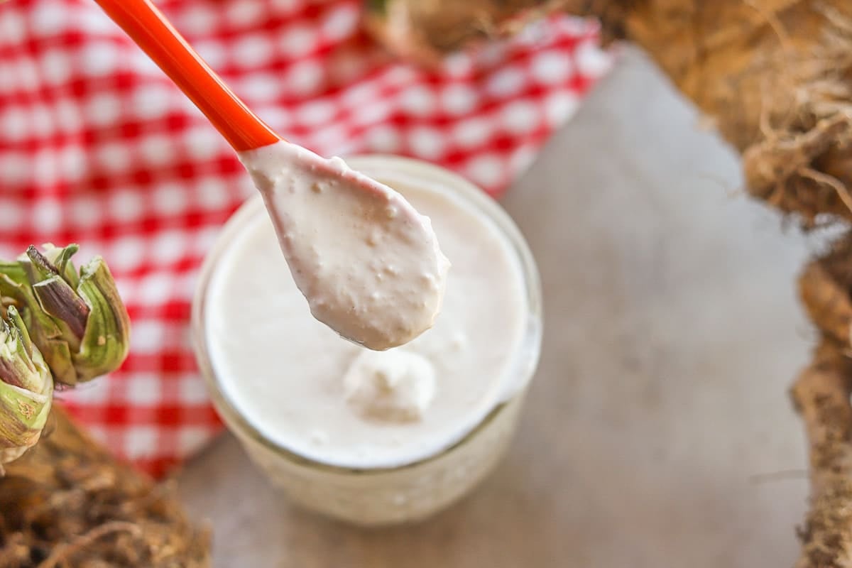 horseradish dripping from spoon into jar