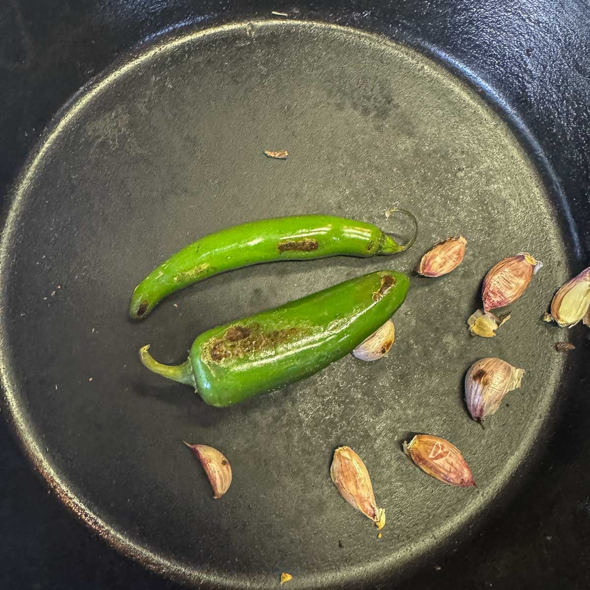 serrano peppers in a pan with garlic cloves