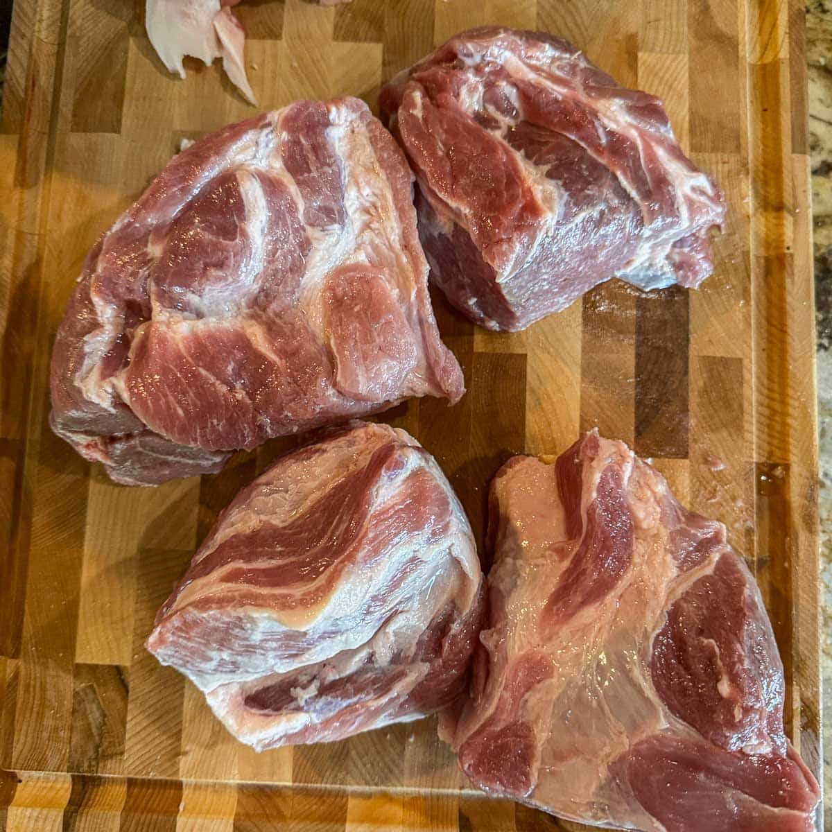 pork shoulder sliced in quarters on a cutting board