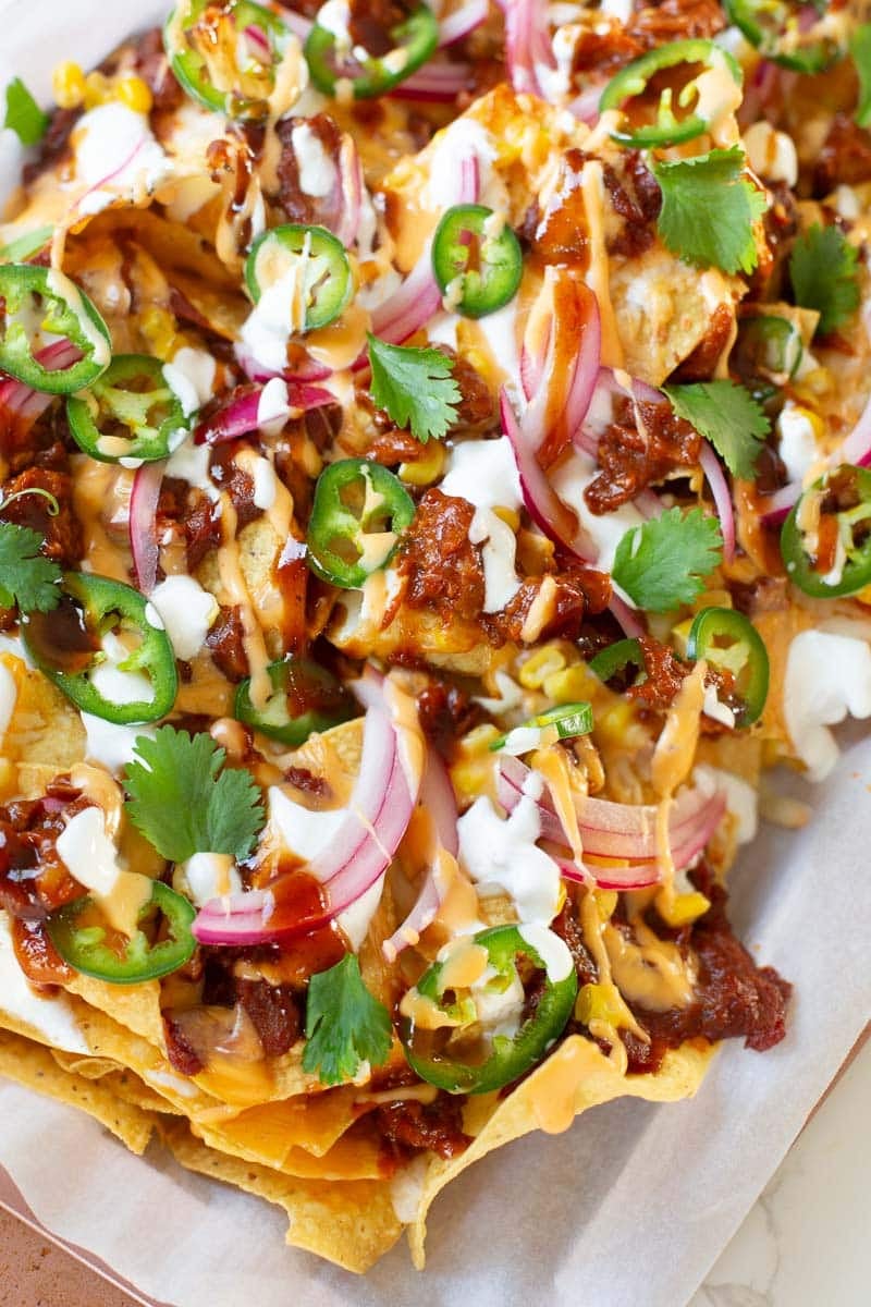 pulled pork nachos topped with pickled onions, cilantro, jalapenos, bbq sauce, etc.