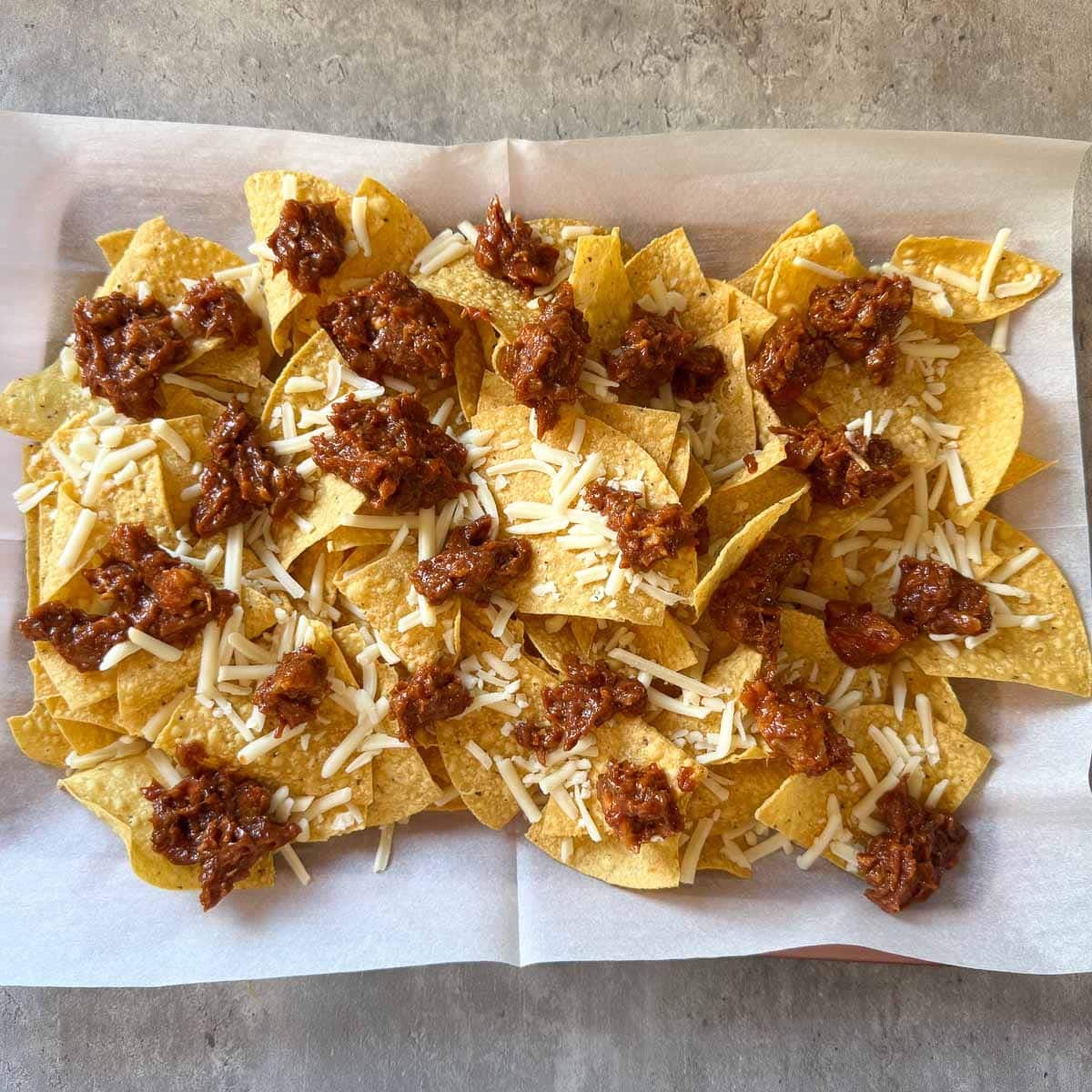 shredded cheese and pulled pork on chips before baking.