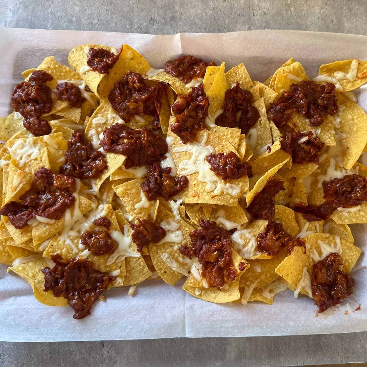 shredded cheese and pulled pork on chips after baking.