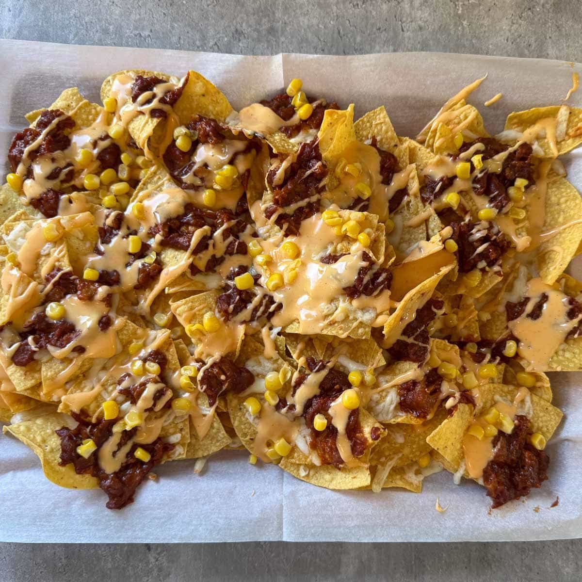 cheese sauce and corn added to pulled pork nachos.