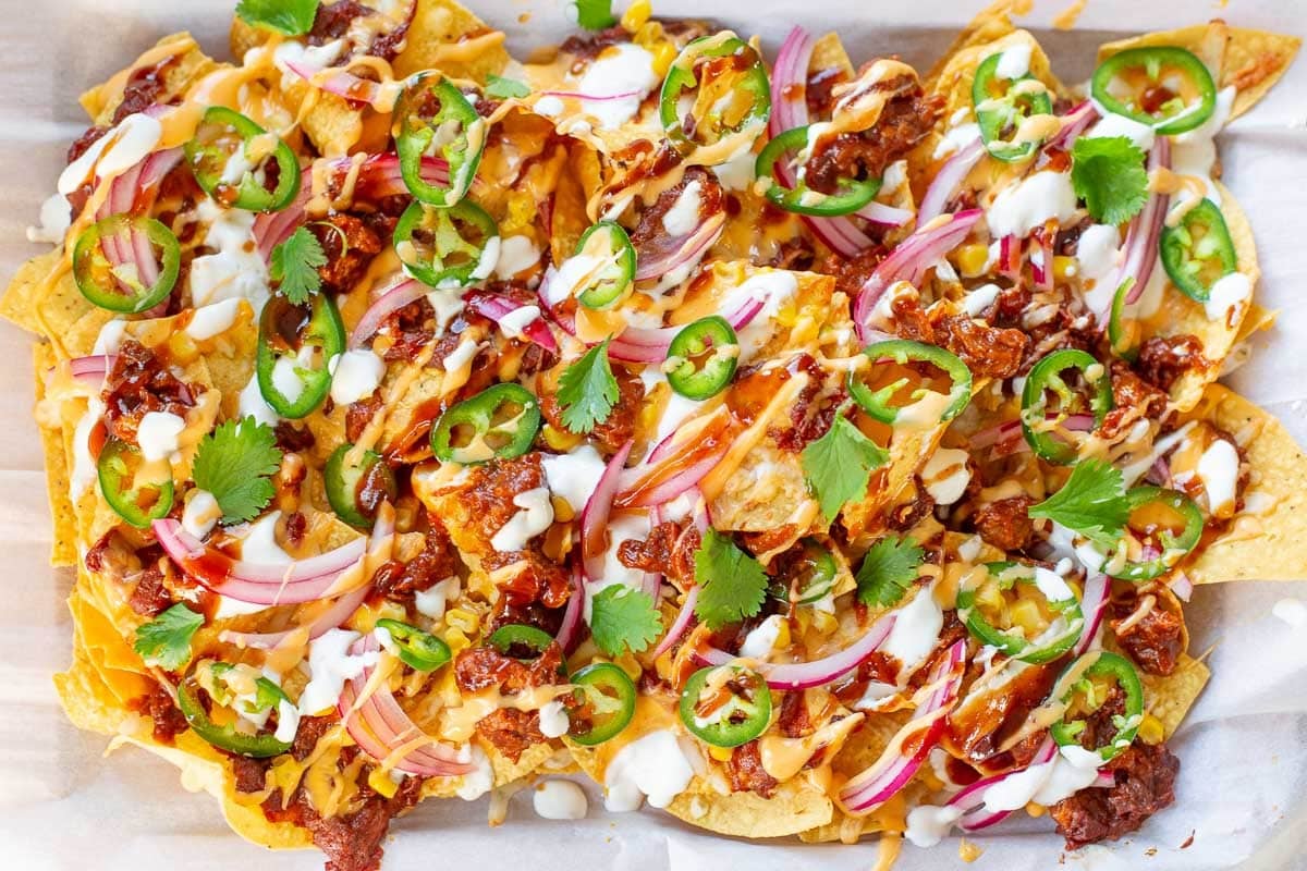 pulled pork nachos recipe in sheet pan topped with fresh cilantro and jalapenos.