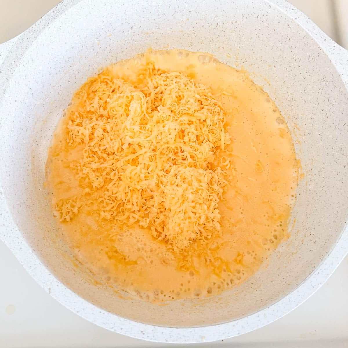 shredded cheddar in cheese sauce before mixing in.