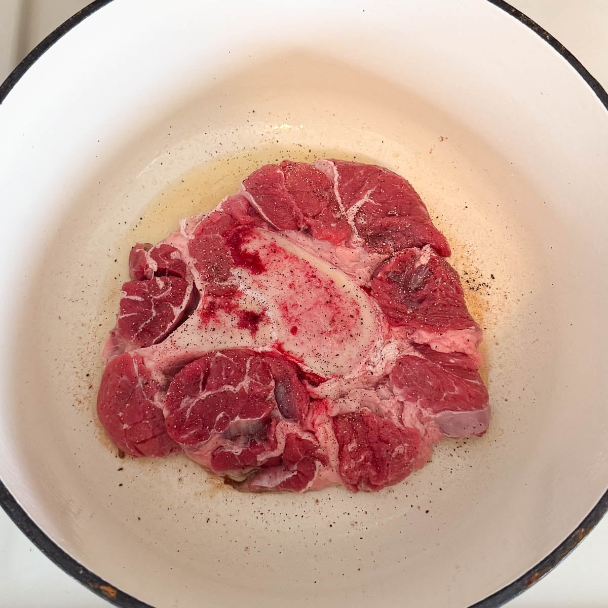 beef shank in pot with oil before searing.