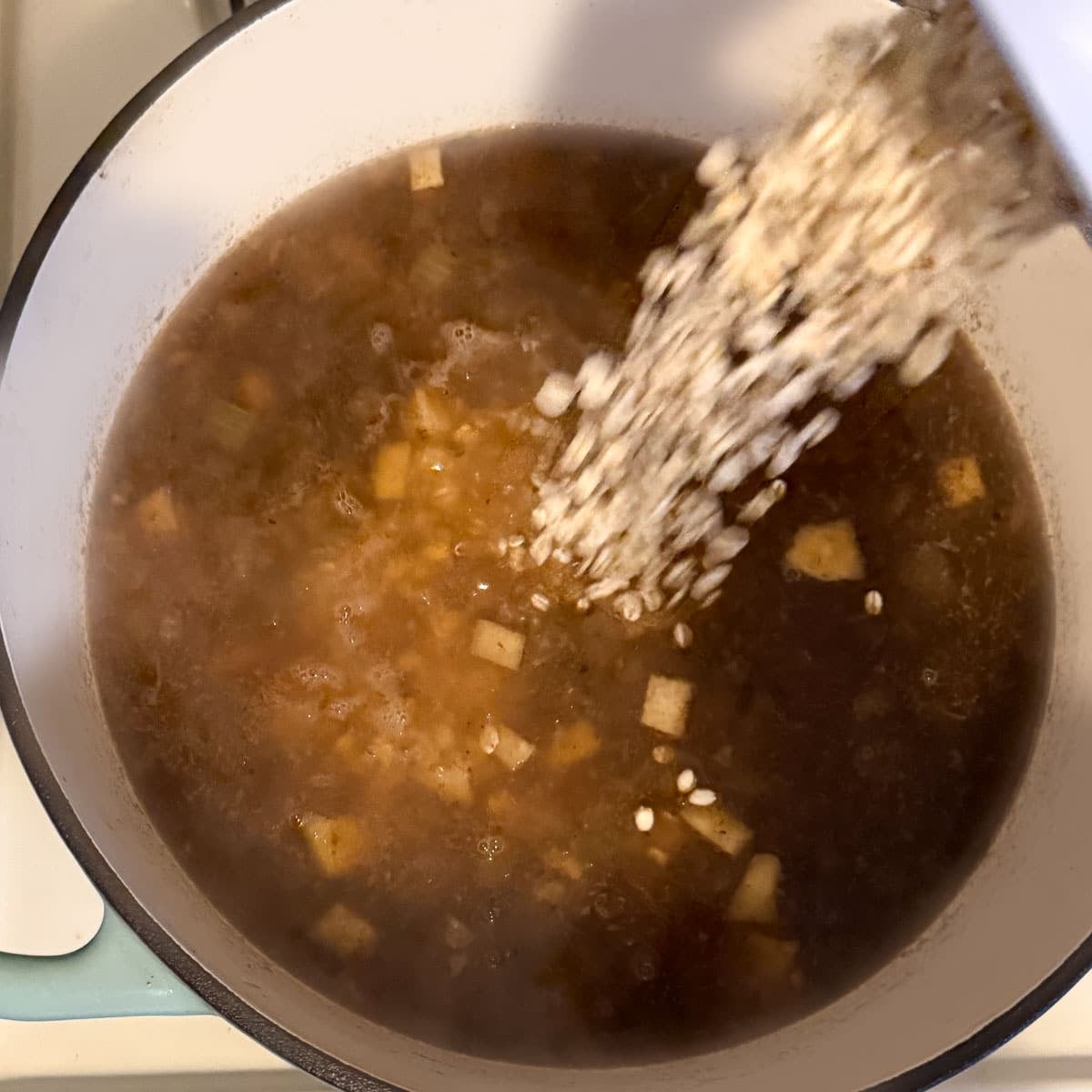 barley being poured into soup.
