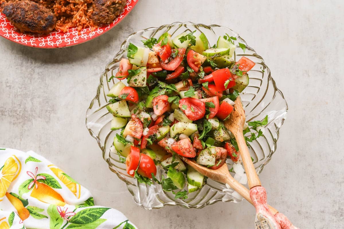 Middle Eastern salad with tongs, bulgur and meat patties and a napkin with lemons 
