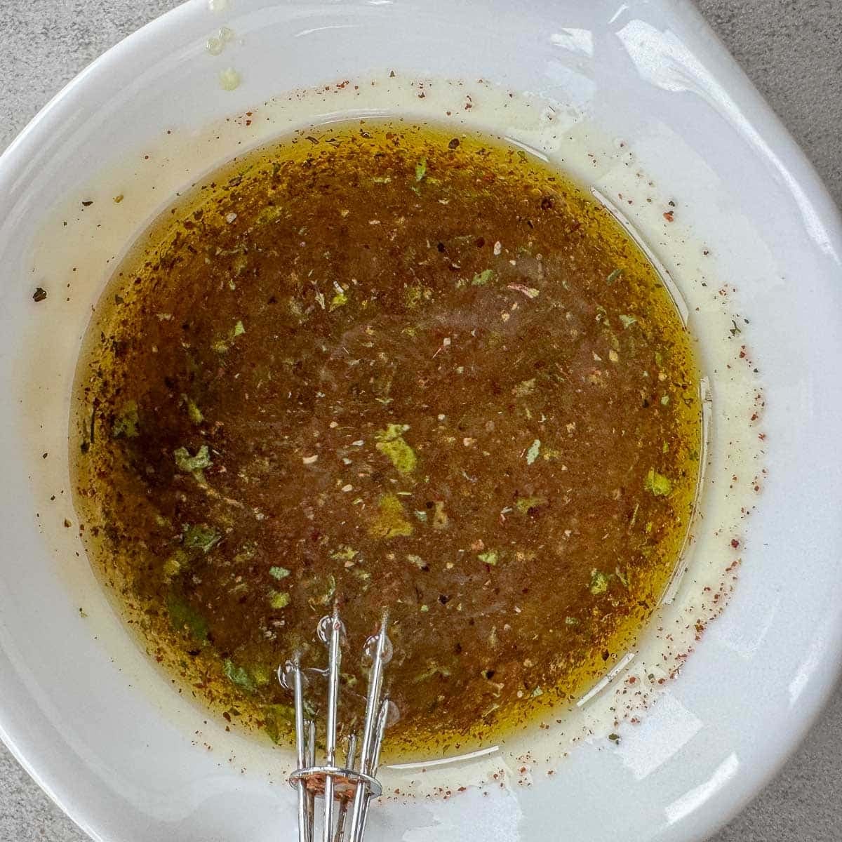 Arab salad dressing in a bowl with a whisk