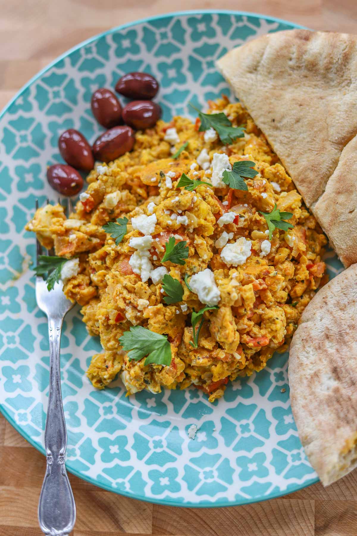 strapatsada (Greek scrambled eggs) with pita bread on a bule and white plate