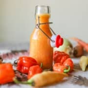 habanero hot sauce in a flip-top bottle with peppers and other veggies around it