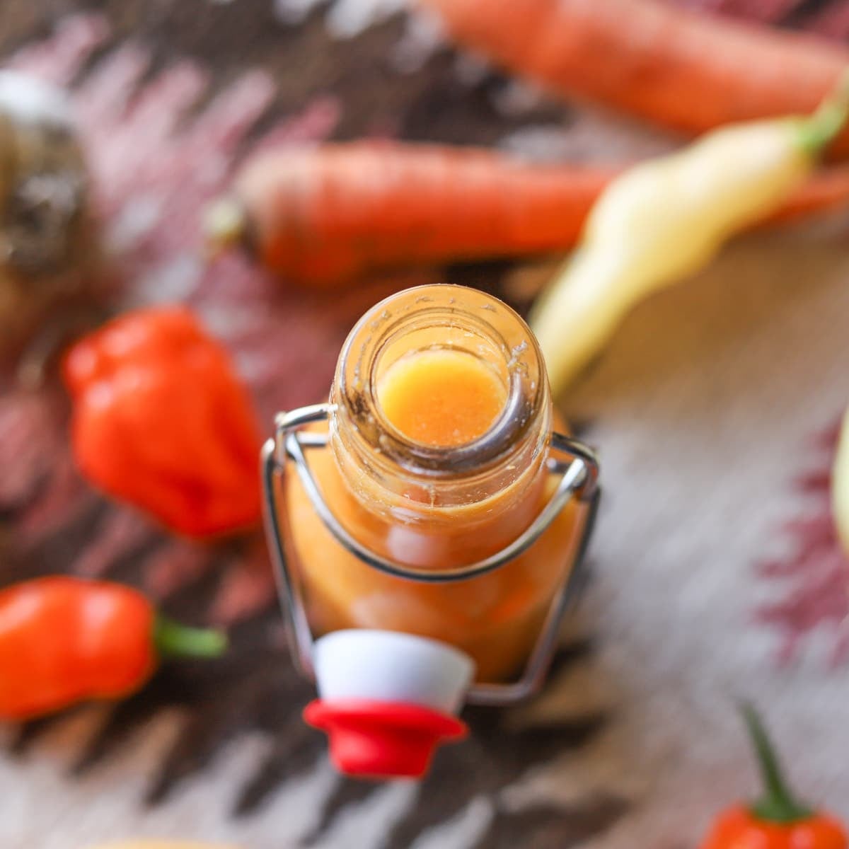 habanero sauce in bottle with peppers around it
