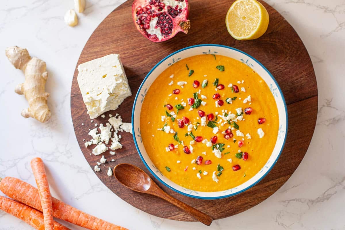 parsnip and carrot soup surrounded by veggies, pomegranate, and feta cheese.