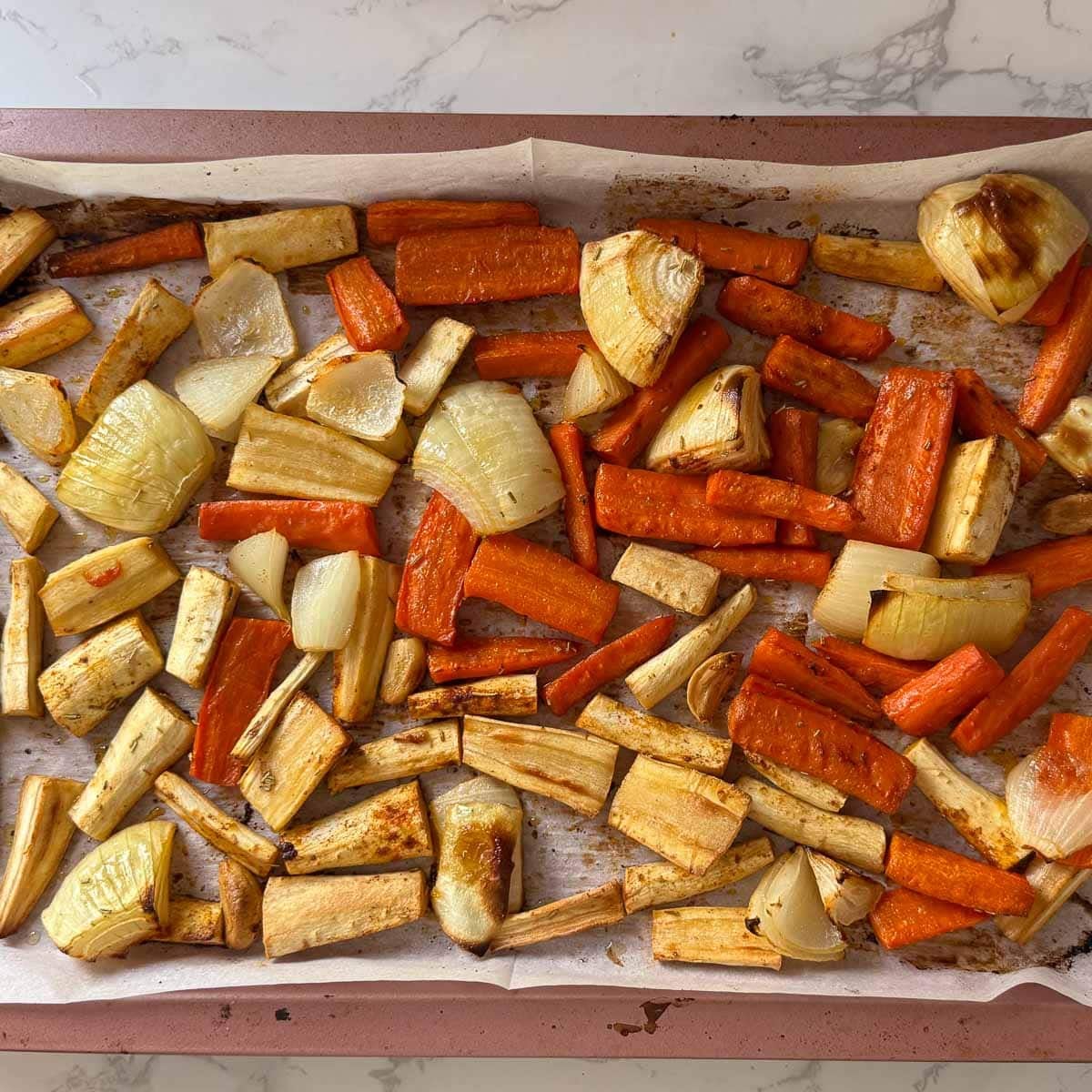 roasted parsnips, carrots, onions, and garlic on sheet pan.