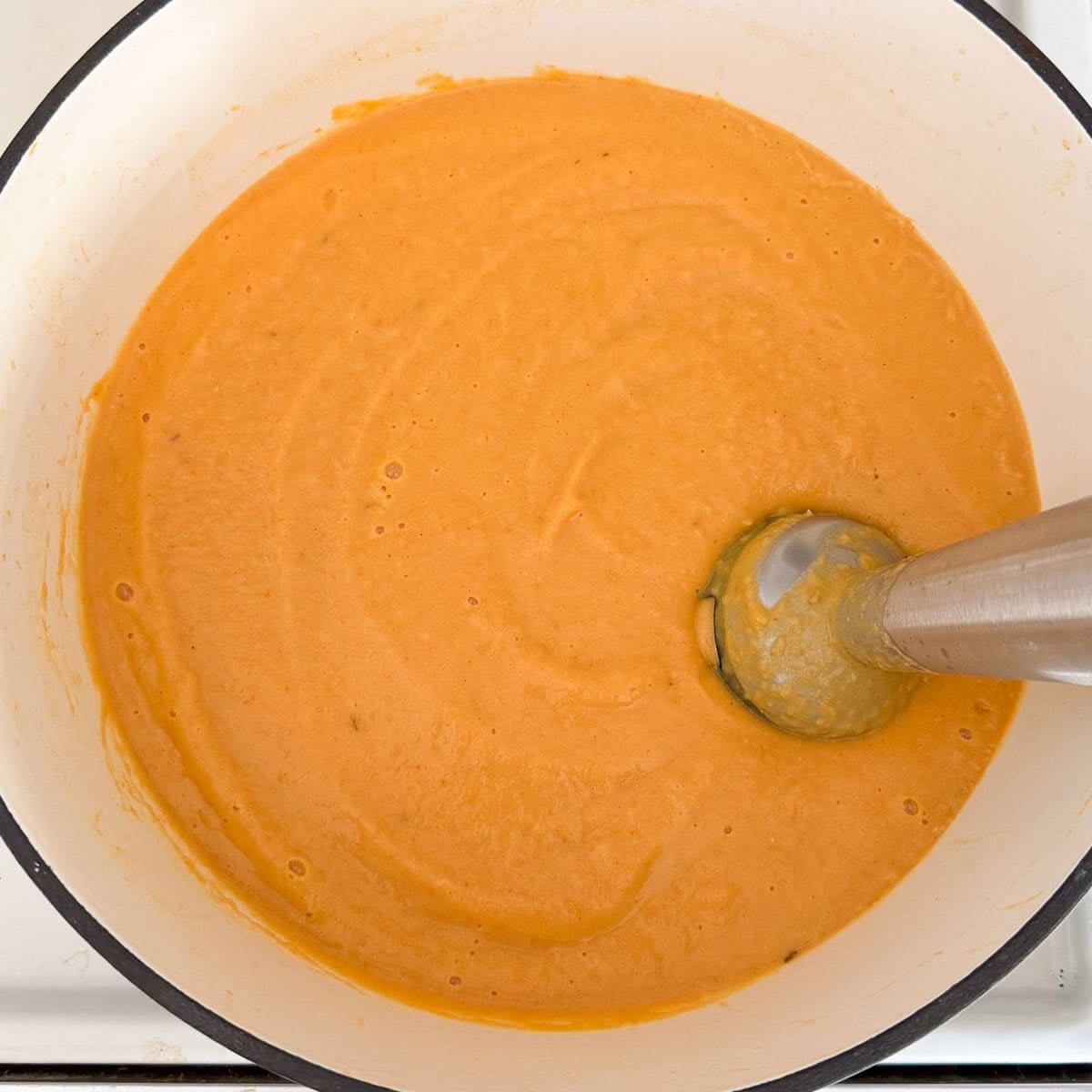 immersion blending parsnip and carrot soup into a creamy consistency.