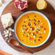 parsnip and carrot soup surrounded by veggies, pomegranate, and feta cheese.