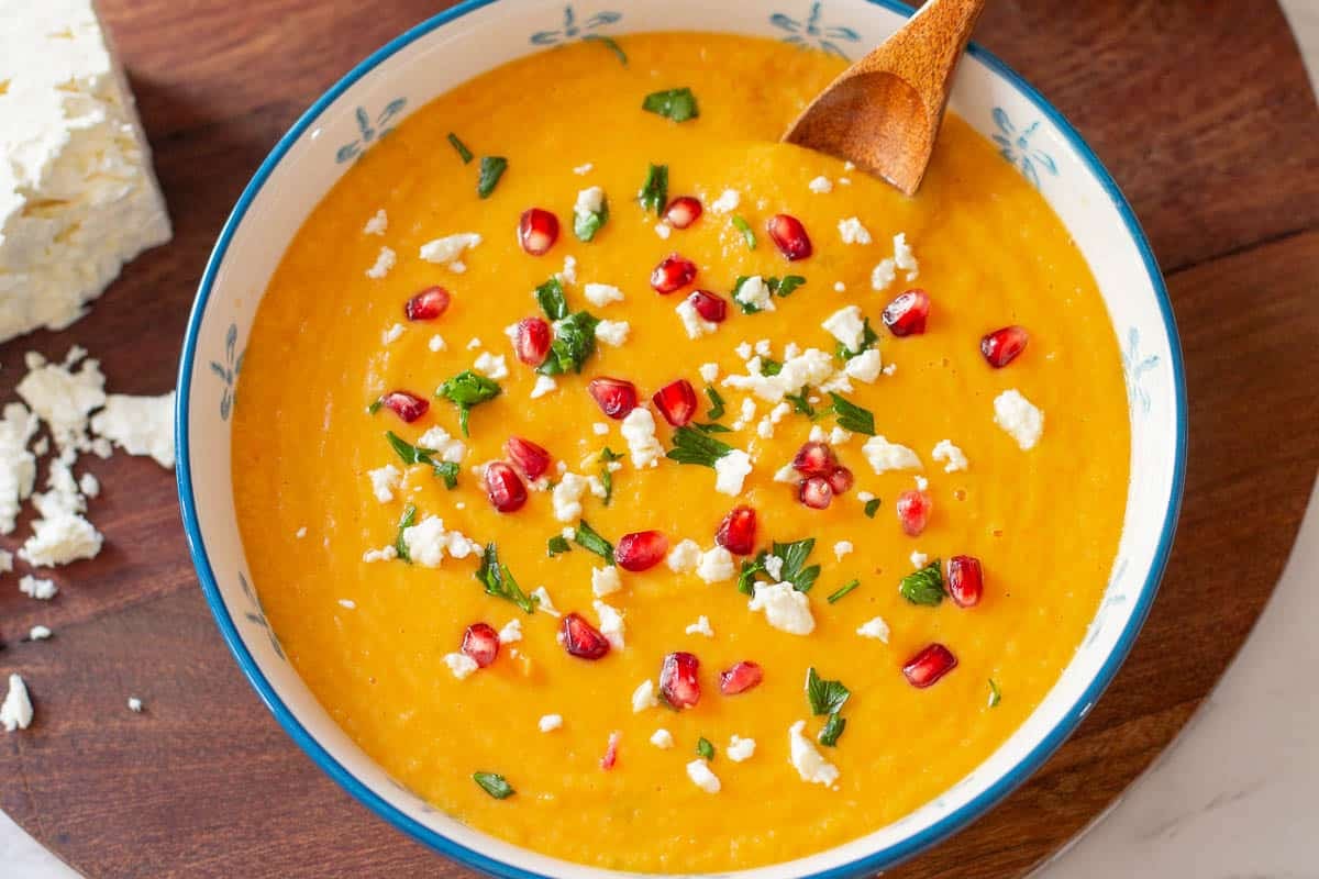 parsnip and carrot soup topped with feta cheese, parsley, and pomegranate seeds.