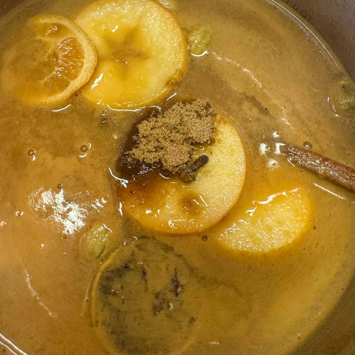 spiced apple cider ingredients in a saucepan, including brown sugar